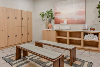 A room with a bench, a cabinet, and a painting on the wall.
